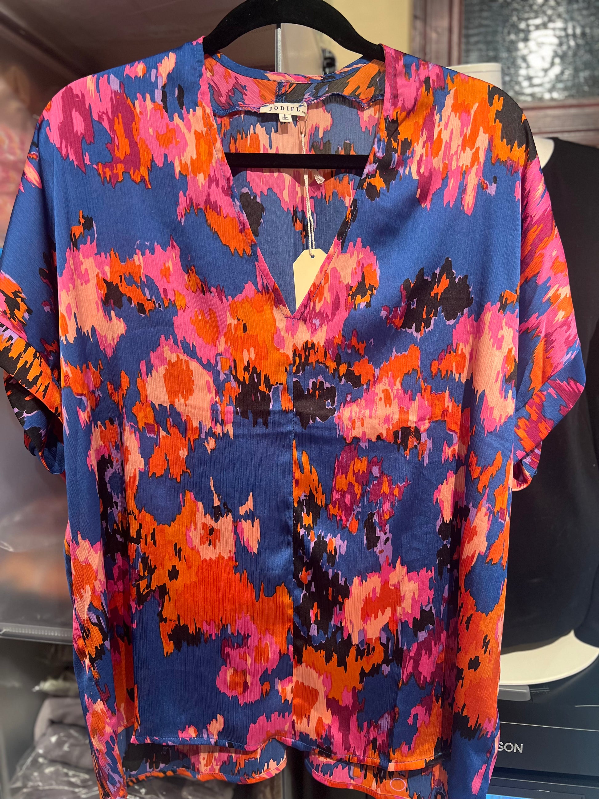 Colorful patterned shirt on a hanger with a visible brand tag.