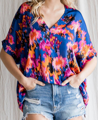 Person wearing a colorful patterned top and denim shorts against a neutral background