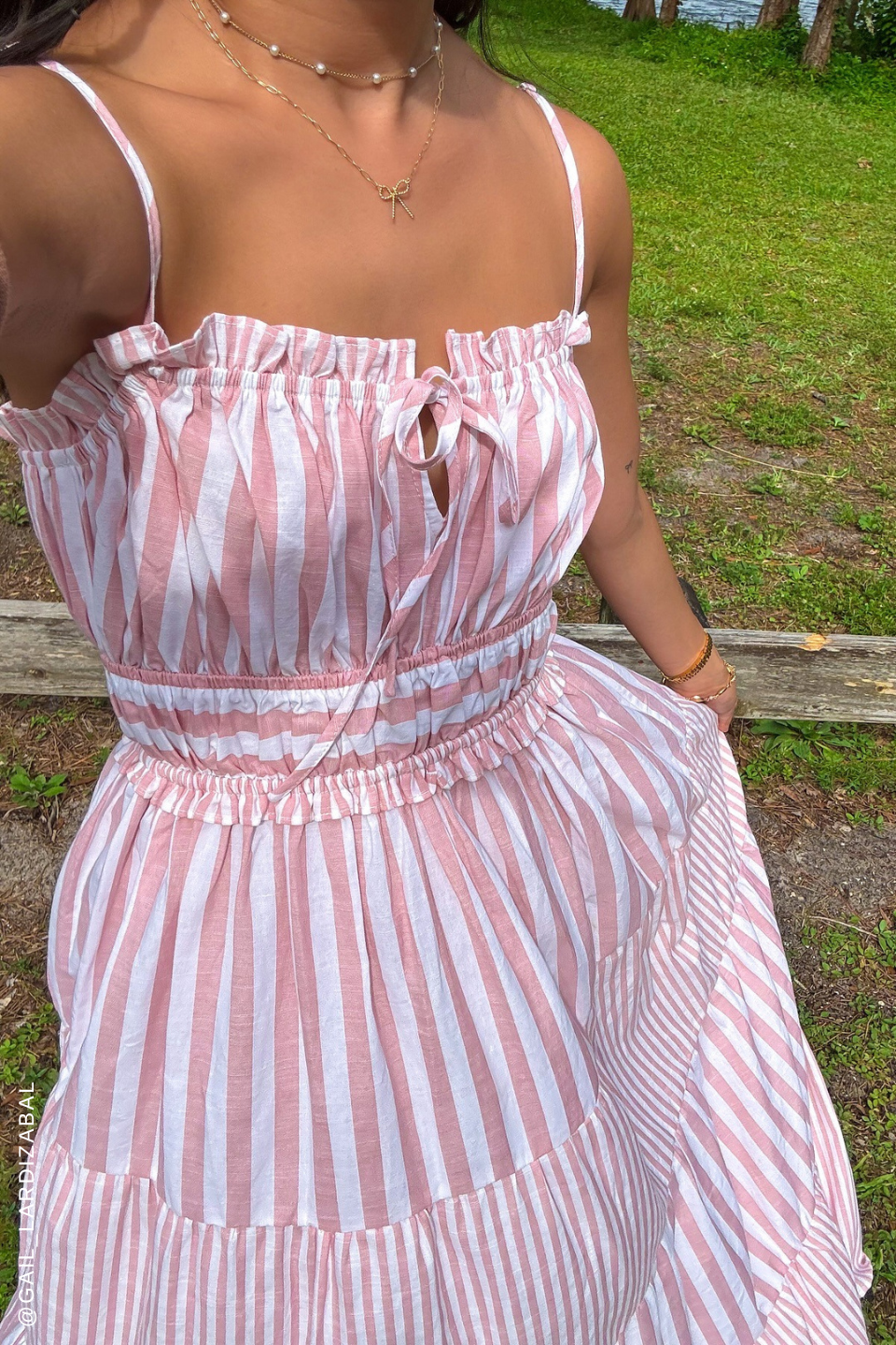 A pink and white striped dress with tiered skirt and ruffle detailing