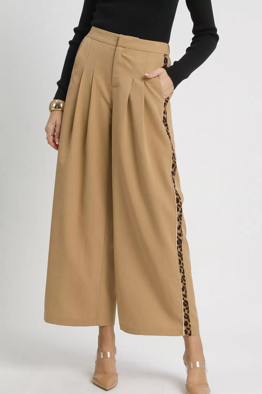 Beige wide-leg pants with leopard print side panels worn by a person on a white background