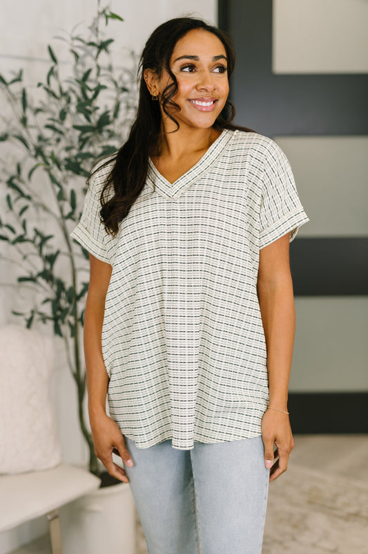 Woman wearing a checkered blouse in a home setting