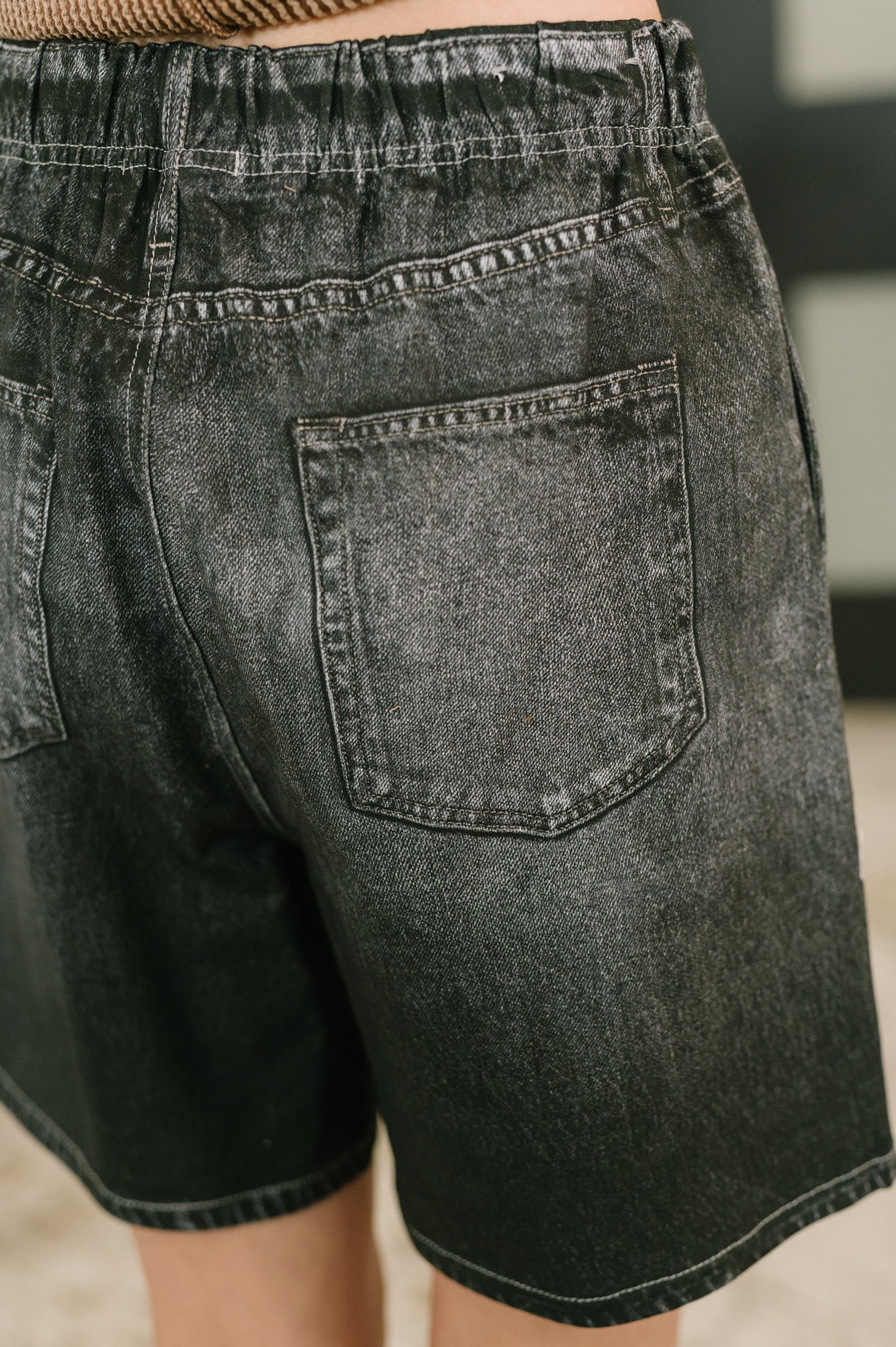 Black denim shorts with a focus on the back pocket.