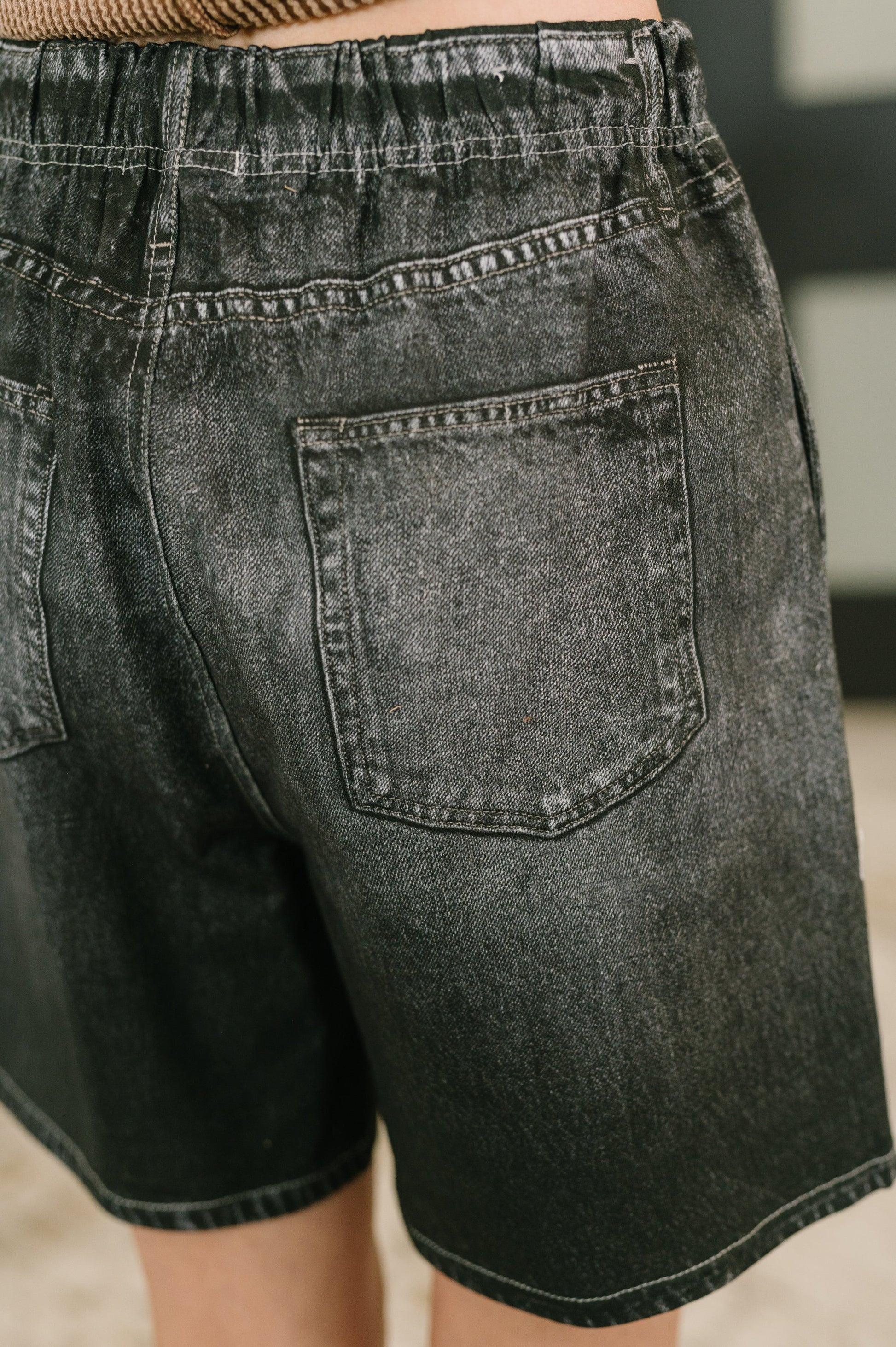 Black denim shorts with a focus on the back pocket.
