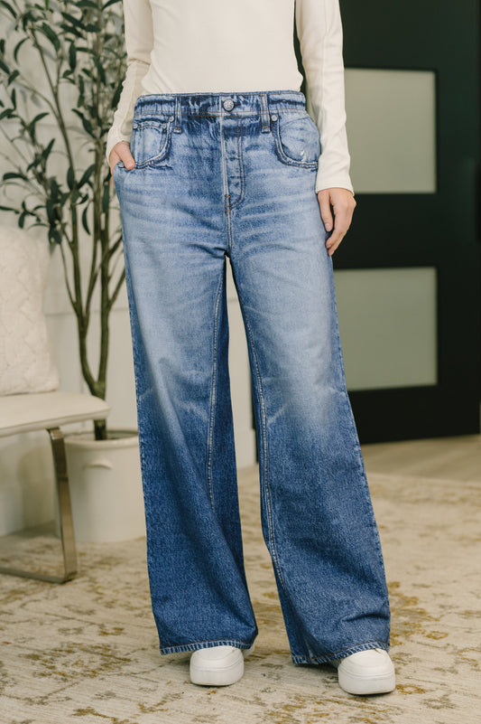 Person wearing blue jeans standing indoors with a blurred background
