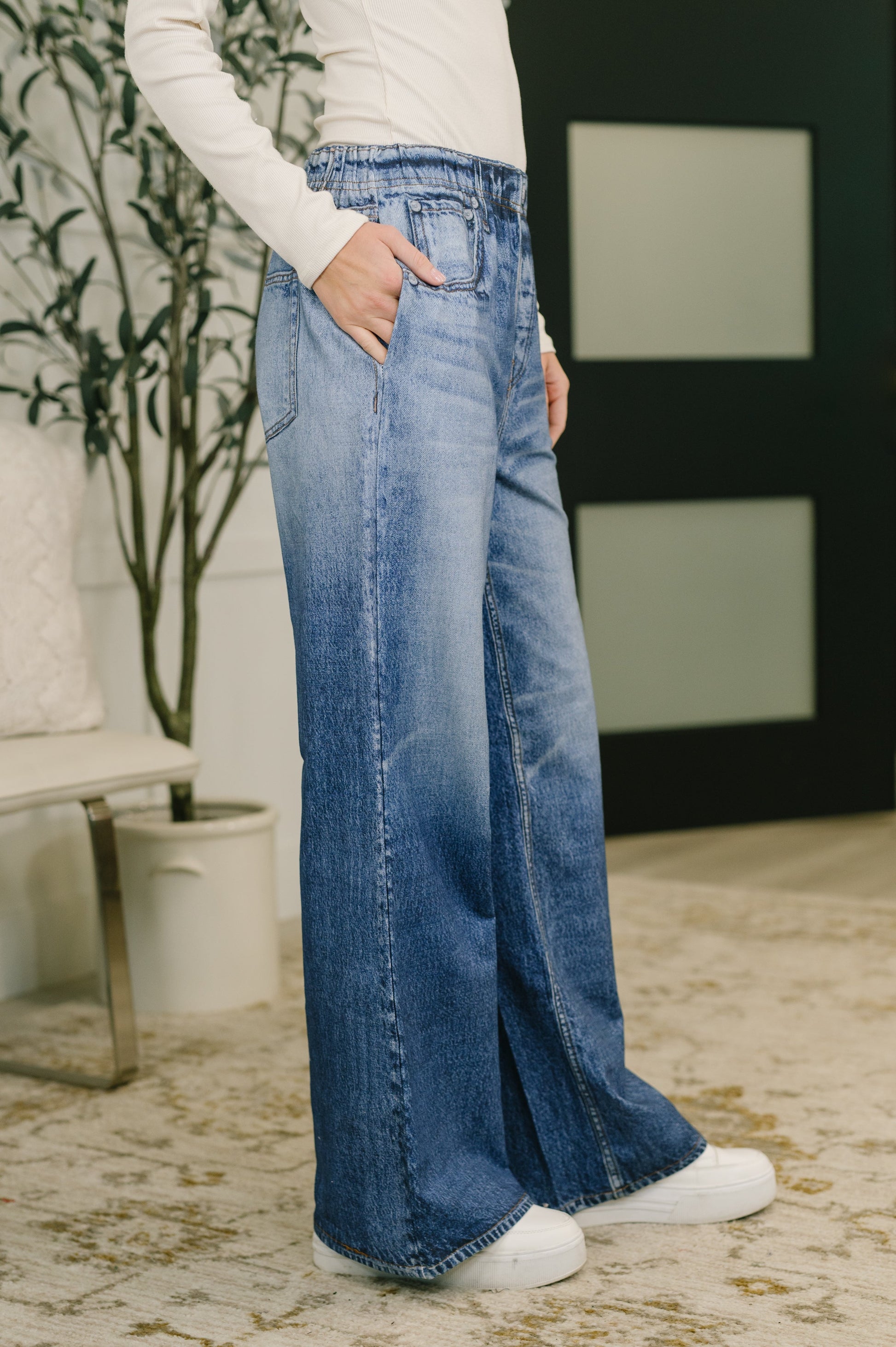 Person wearing blue wide-leg jeans indoors with a neutral background
