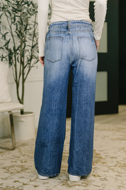 Person wearing blue wide-leg jeans in an indoor setting