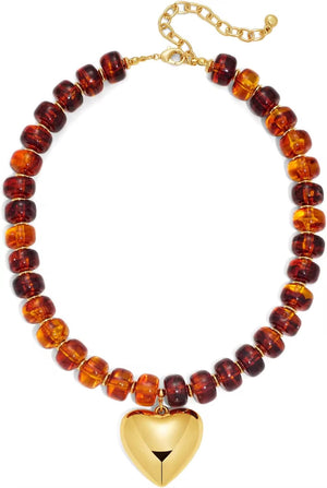 Necklace with amber beads and a gold heart pendant on a white background