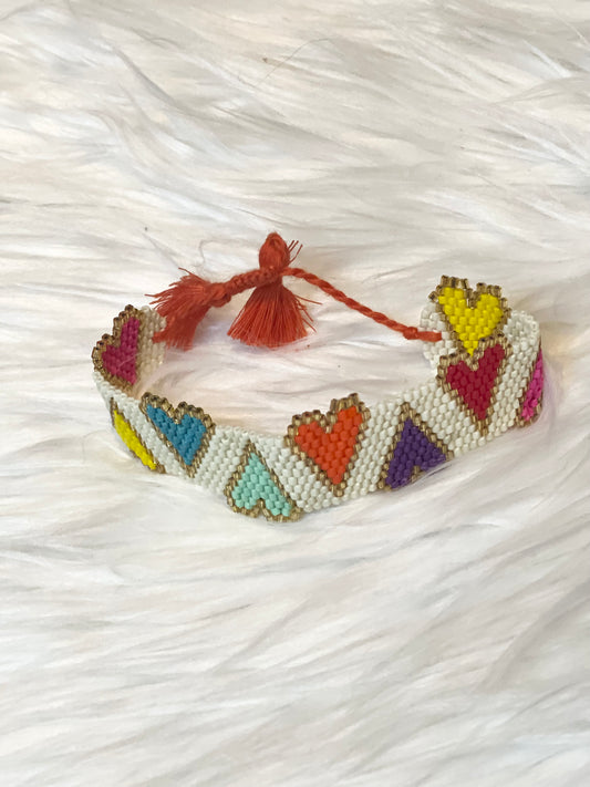 Colorful beaded bracelet with heart patterns on a white textured background