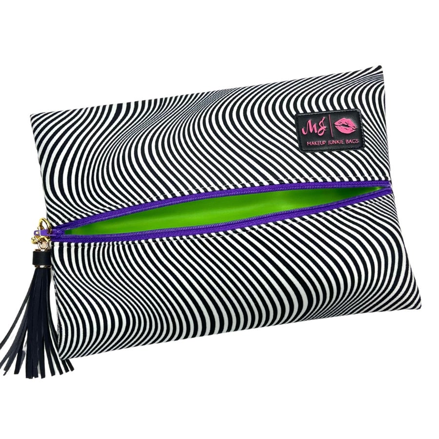 Makeup bag with black and white striped pattern, green interior, and purple zipper on a white background.