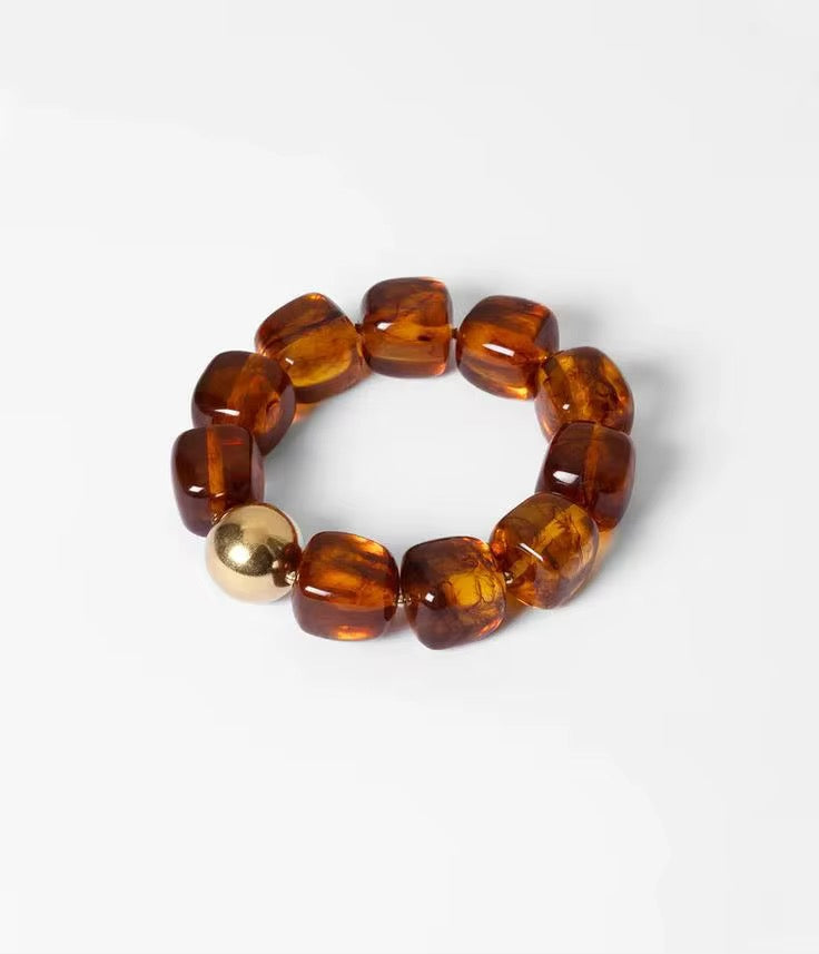 Bracelet with brown beads and a gold accent on a white background