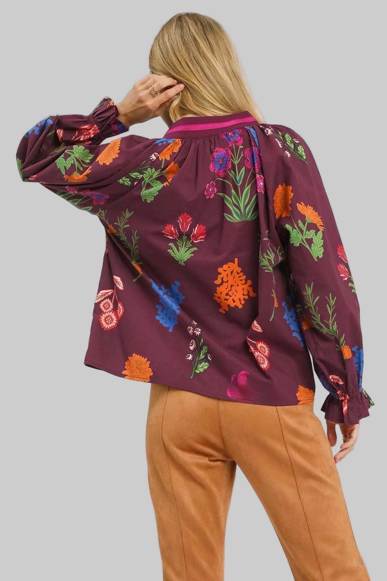Person wearing a burgundy floral blouse with colorful patterns on a white background