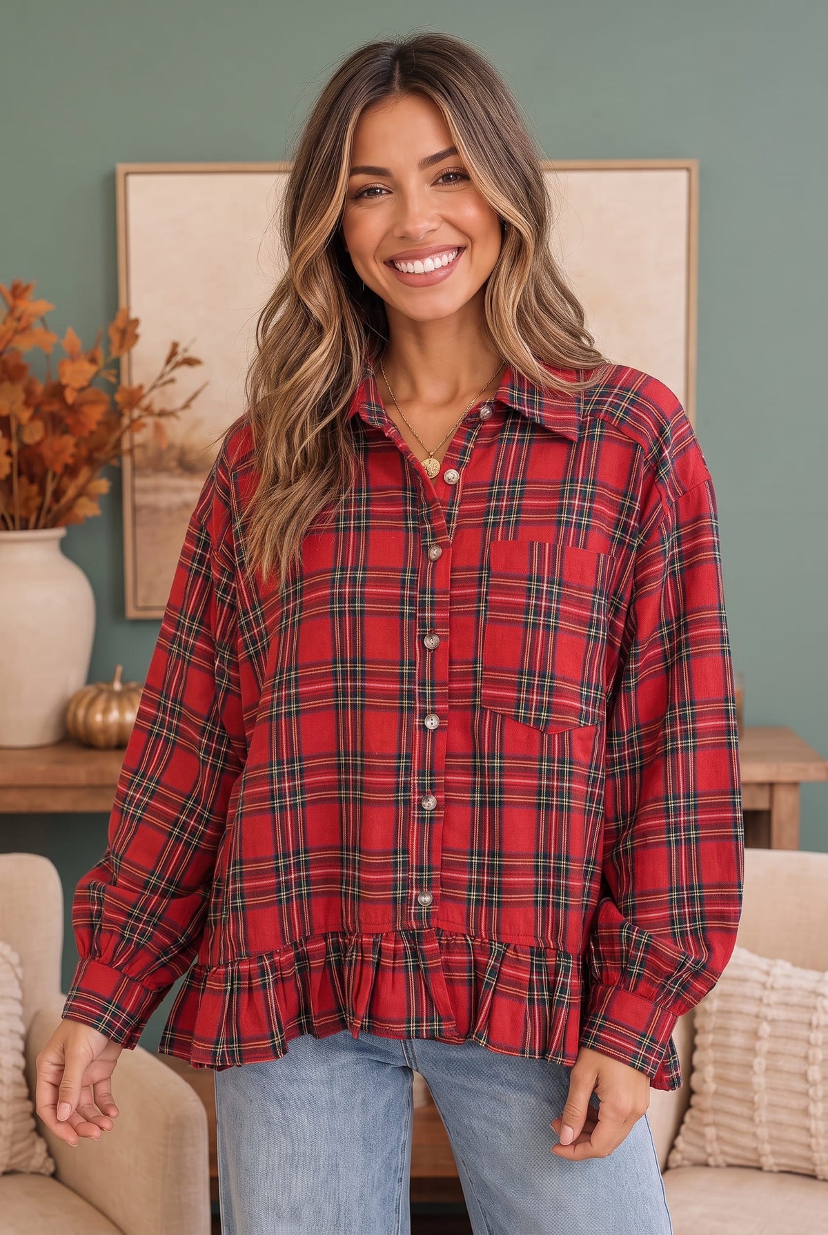 A woman wearing a red and black plaid button-up shirt with a ruffled hem, paired with light blue jeans, standing in a cozy living room setting.