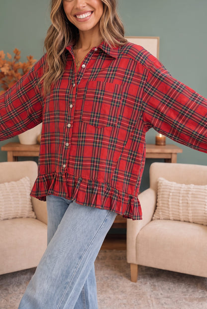 A woman wearing a red plaid button-up shirt with a ruffled hem and light blue jeans, standing in a cozy living room setting.