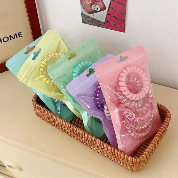 Colorful hair ties in clear packaging on a wicker basket with a blurred background