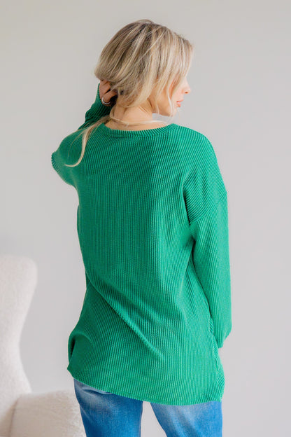 Person wearing a green sweater and blue jeans against a white background