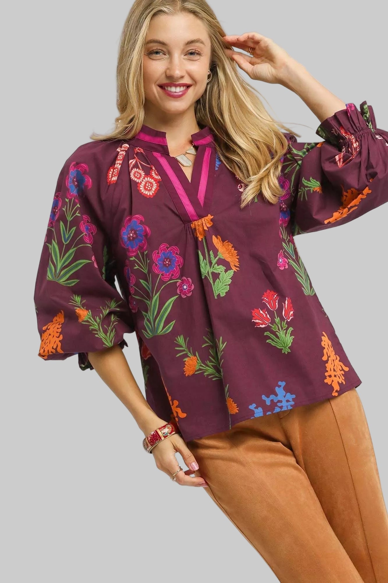 Woman wearing a burgundy embroidered blouse with colorful floral patterns on a white background