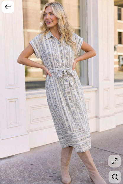 Woman wearing a patterned dress standing in front of a building.