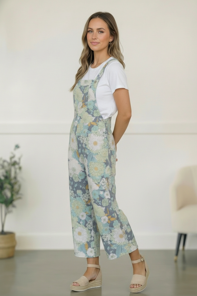 Woman wearing floral overalls and a white shirt in a minimal indoor setting