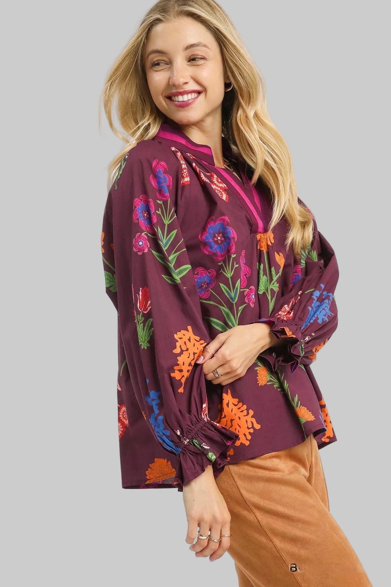 Woman wearing a burgundy blouse with colorful floral patterns on a white background
