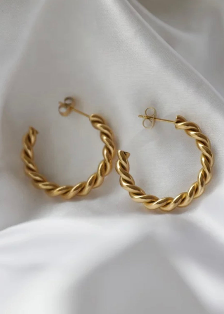 Gold hoop earrings on a white fabric background