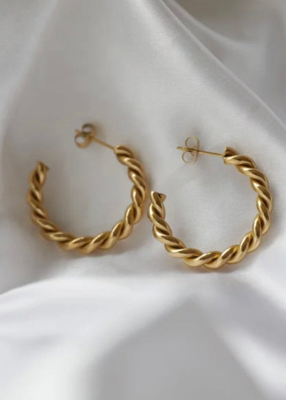 Gold hoop earrings on a white fabric background