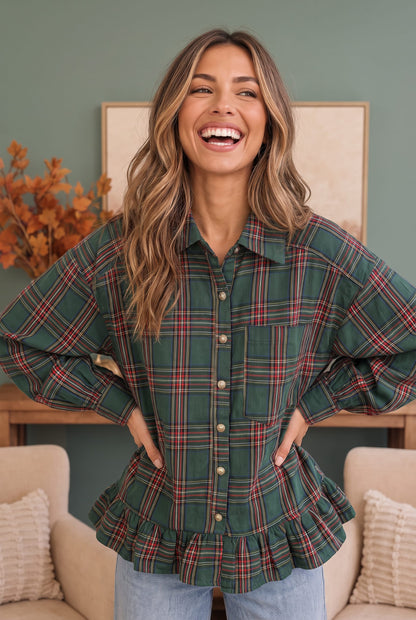 A woman wearing a green plaid button-up shirt with balloon sleeves and a ruffled peplum hem, paired with light blue jeans, standing in a cozy living room setting.
