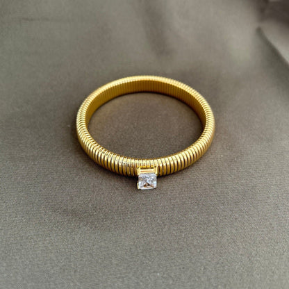 Gold bracelet with a diamond clasp on a gray background