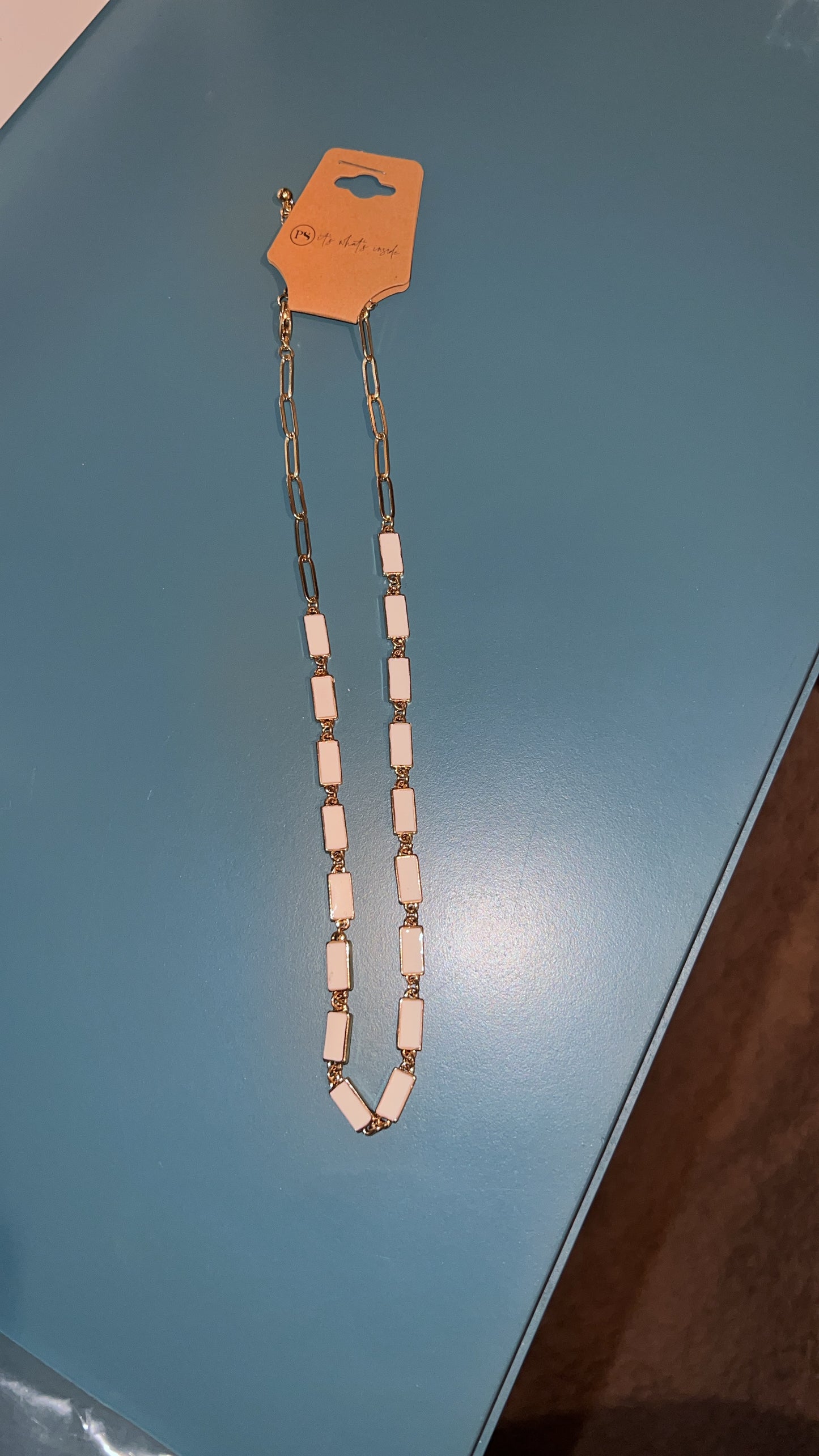Necklace with a pink and silver design on a blue surface
