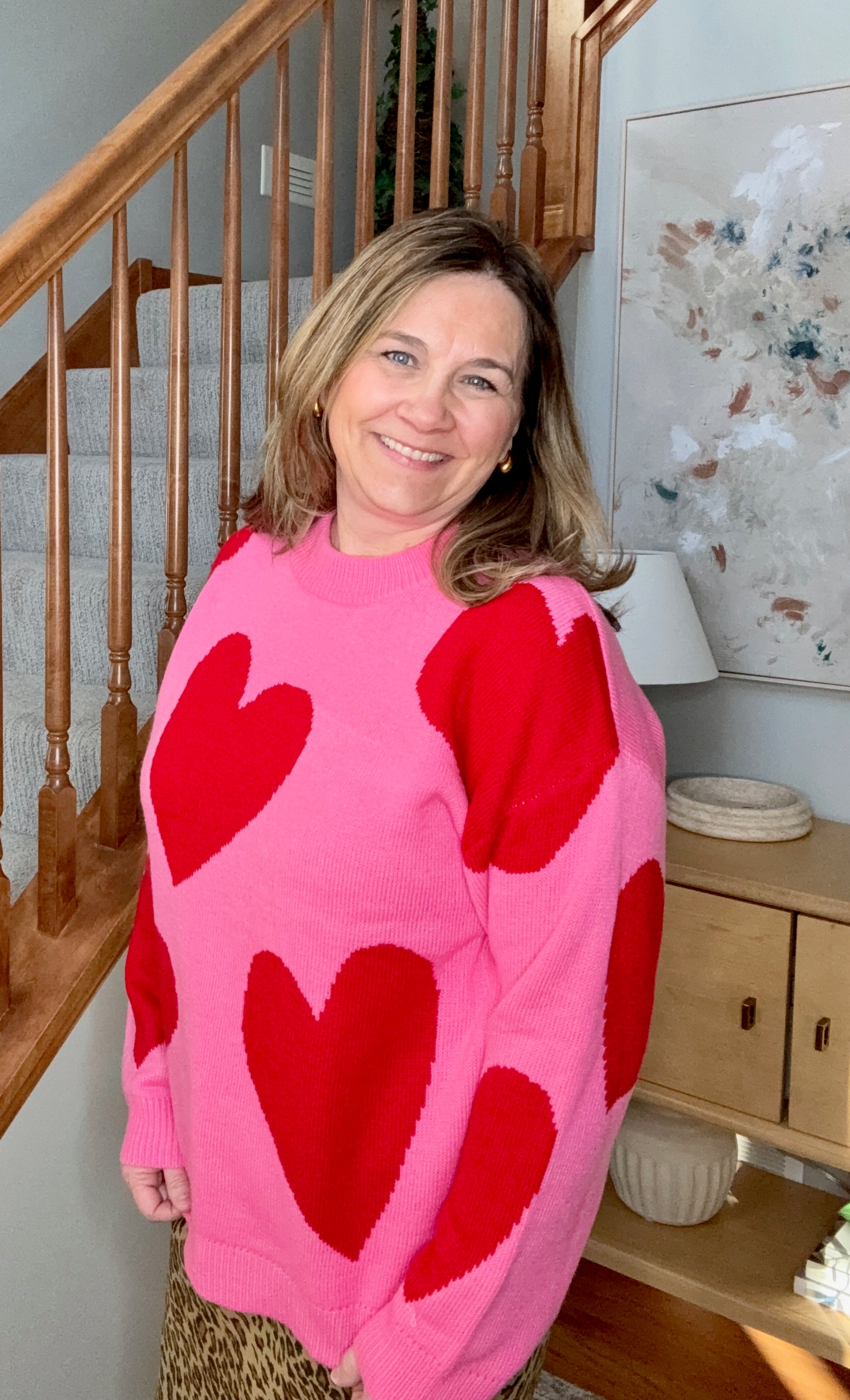 Woman wearing a pink sweater with red hearts in a home setting