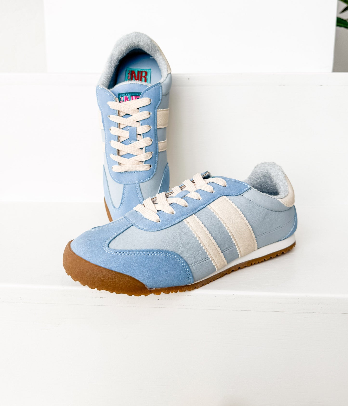 Pair of blue sneakers with white laces on a white background