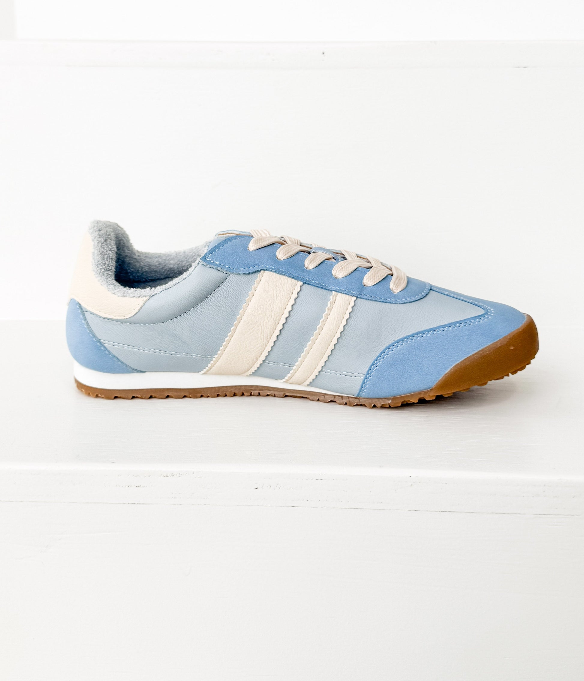 Light blue sneaker with white stripes on a white background