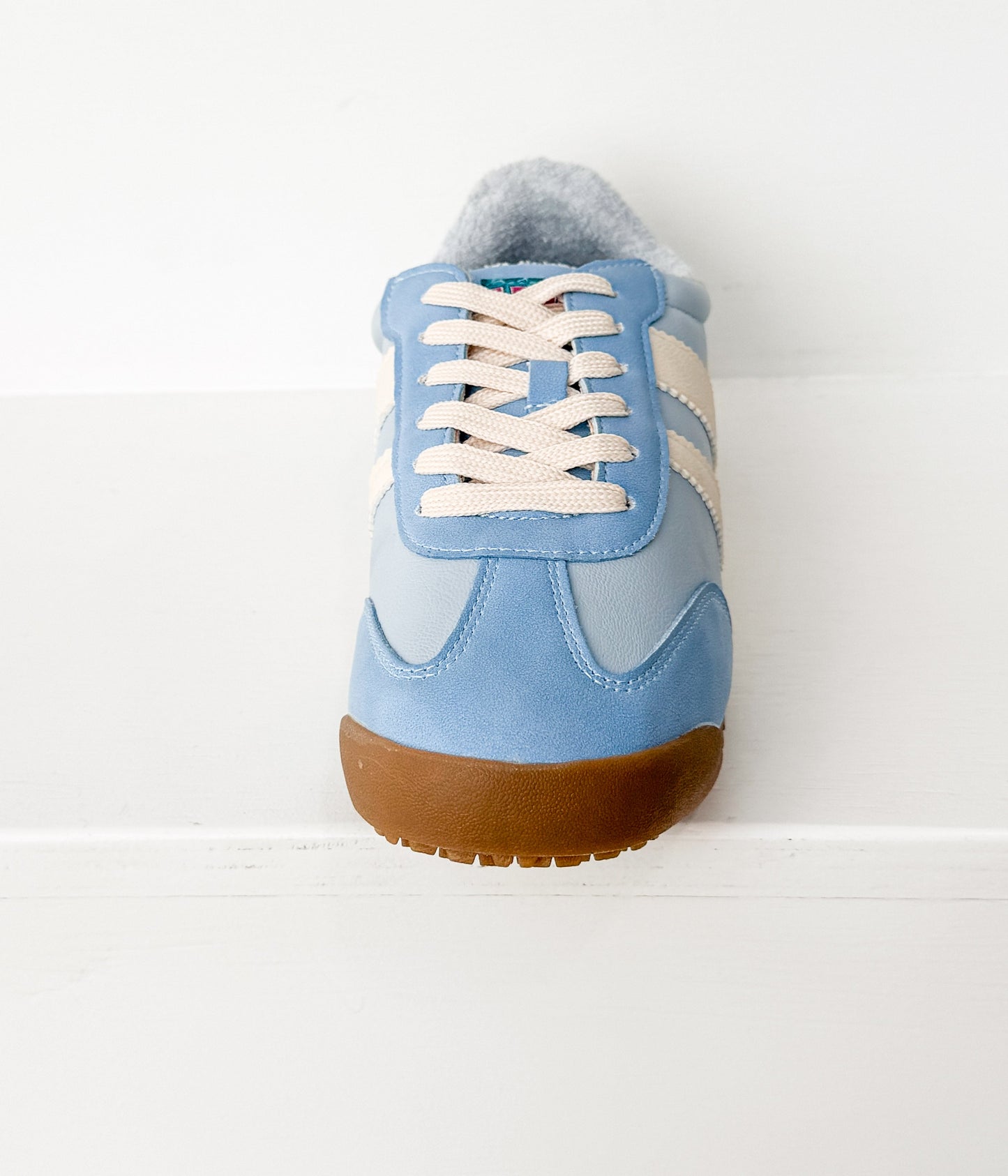 Light blue sneaker with white laces on a light gray background