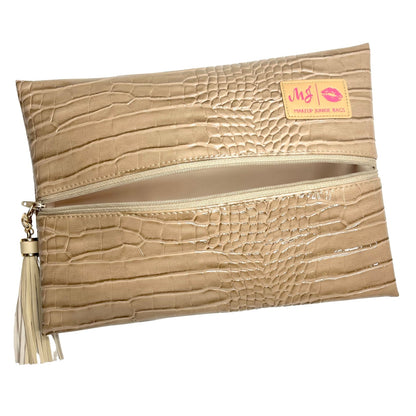 A beige faux-crocodile leather clutch pouch with a horizontal zipper, featuring a cream tassel on the left and a small yellow brand label on the top right.