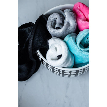 Colorful folded towels in a white bowl on a marble surface