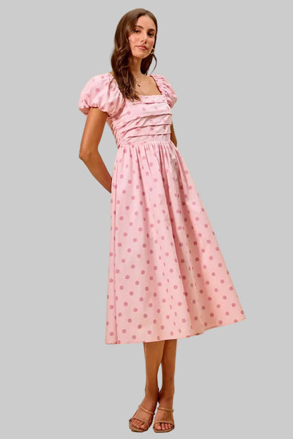 Woman wearing a pink dress with puff sleeves on a beige background