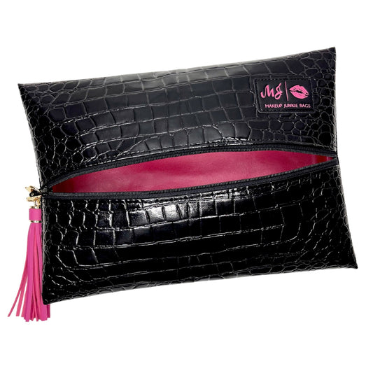 Black crocodile-embossed makeup pouch with a pink interior lining, a pink tassel zipper pull, and a pink brand patch on the top right.