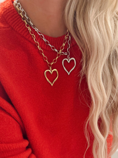 Person wearing a red sweater with layered heart-shaped necklaces.