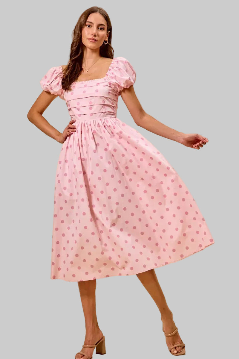 Woman wearing a pink polka dot dress on a beige background