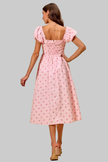 Woman wearing a pink dress with a subtle pattern on a beige background