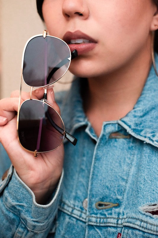 Person wearing a denim jacket holding sunglasses
