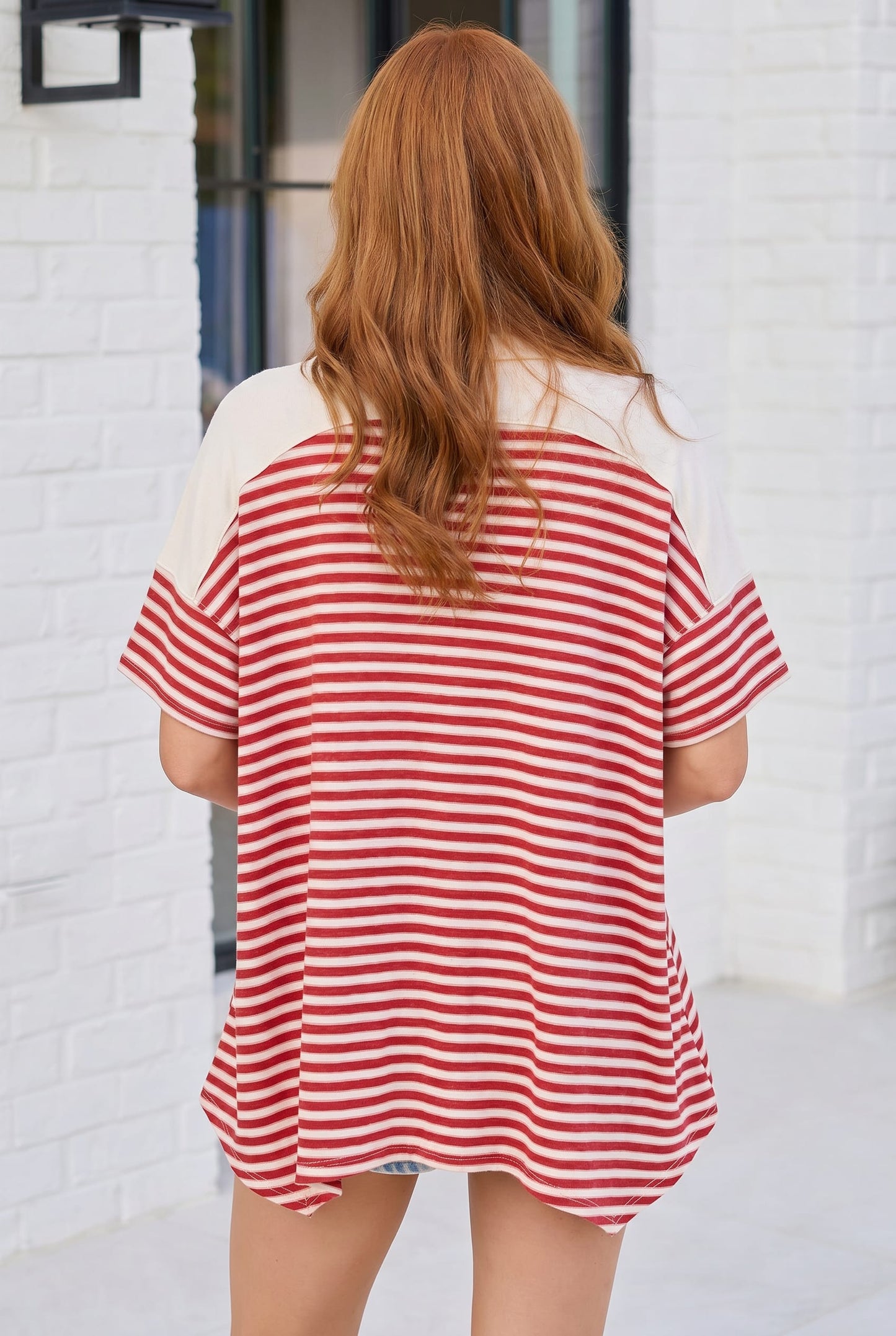 Person wearing a red and white striped shirt in front of a white brick wall.
