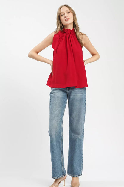 Woman wearing a red sleeveless top and blue jeans on a white background