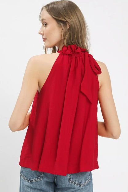 Woman wearing a red halter top with a bow detail on a white background