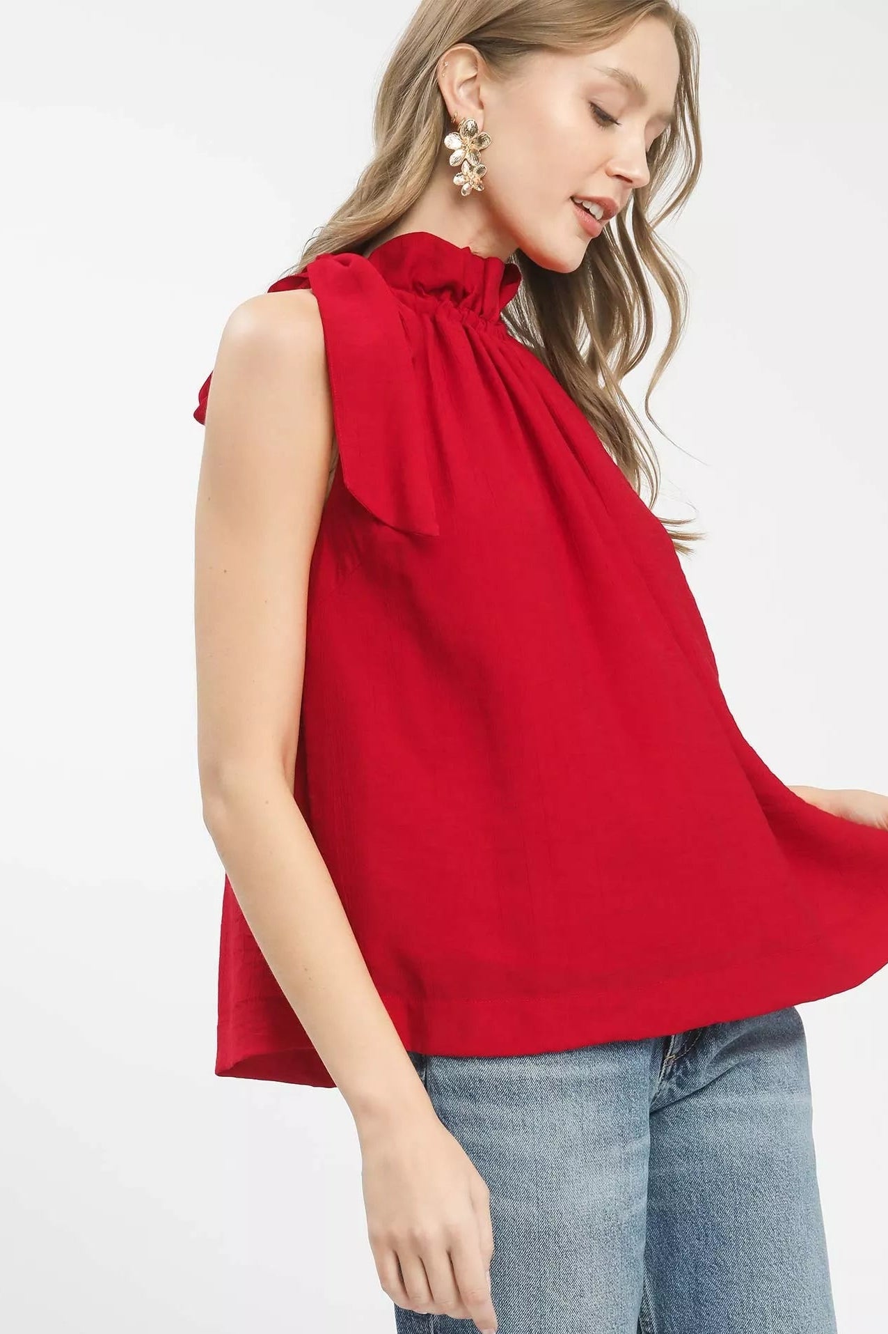 Woman wearing a red sleeveless top with a bow detail on a white background