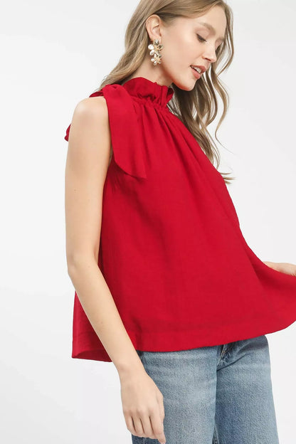 Woman wearing a red sleeveless top with a bow detail on a white background