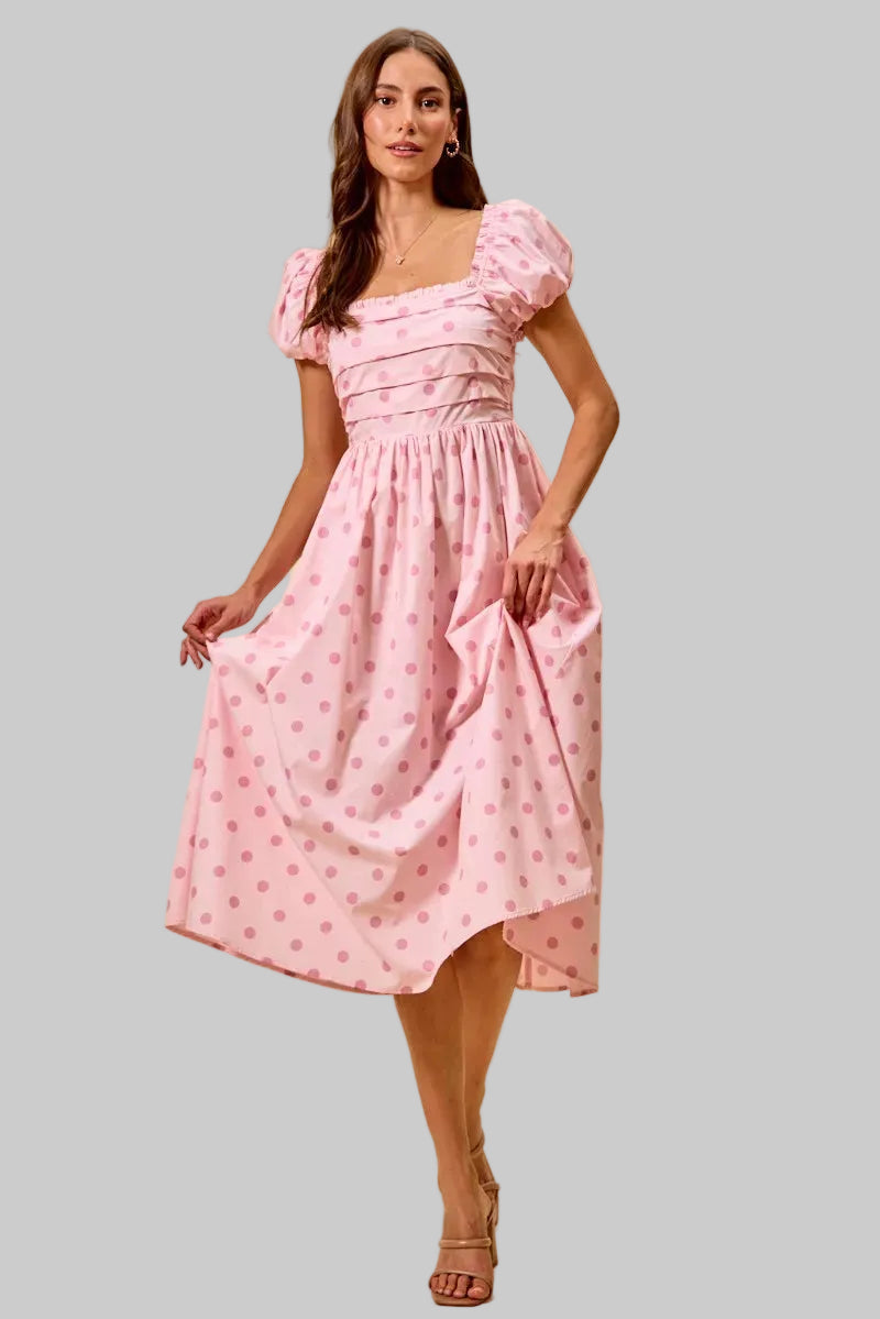 Woman wearing a pink dress with puff sleeves against a beige background