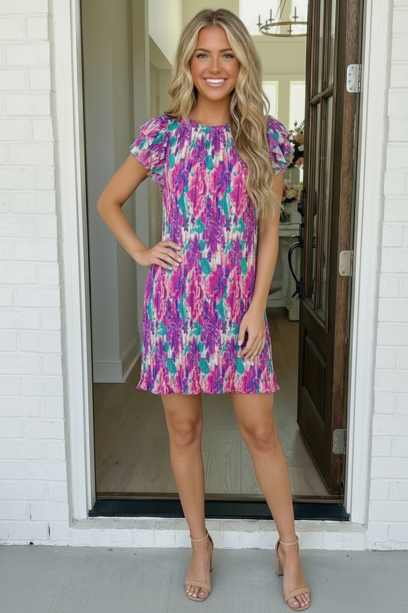 Woman wearing a colorful dress standing in a doorway.