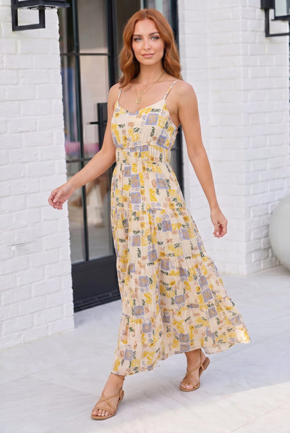 Woman wearing a floral dress standing in front of a white brick wall.