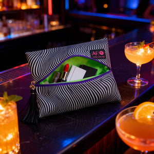 Striped makeup bag with cosmetics on a bar counter with cocktails