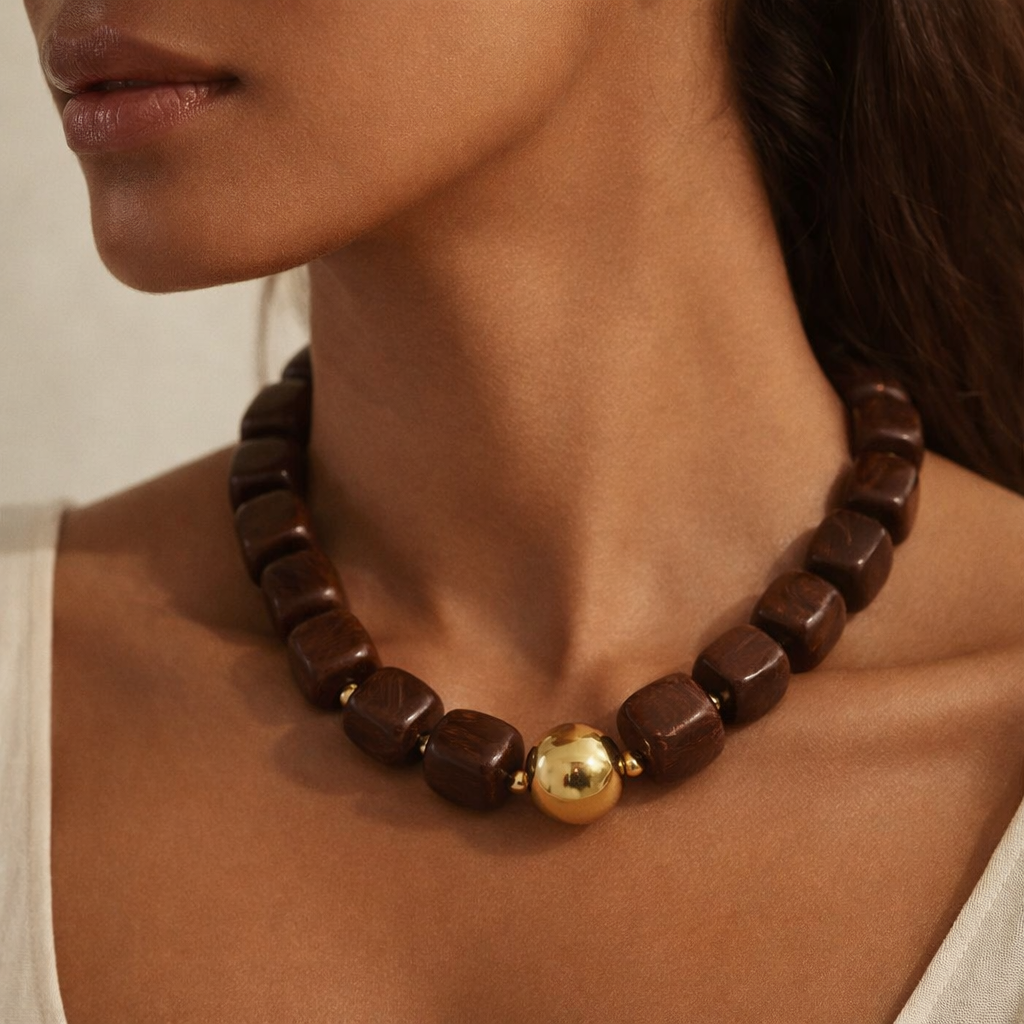 Close-up of a woman wearing a brown beaded necklace with a gold accent.